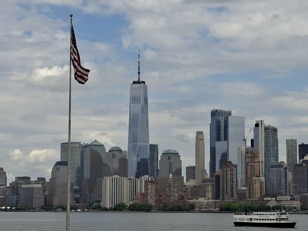 New york city skyline, american flag, and boat on water.