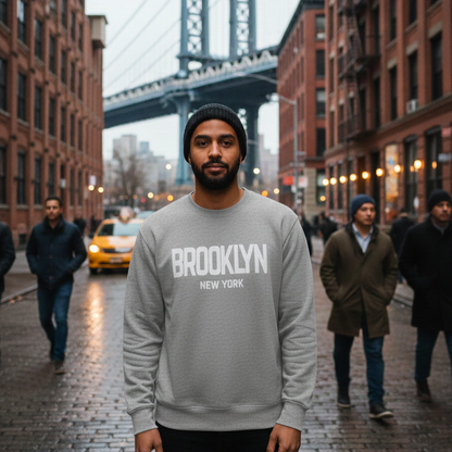 Man wearing a gray 'Brooklyn New York' sweatshirt with the Manhattan Bridge in the background.